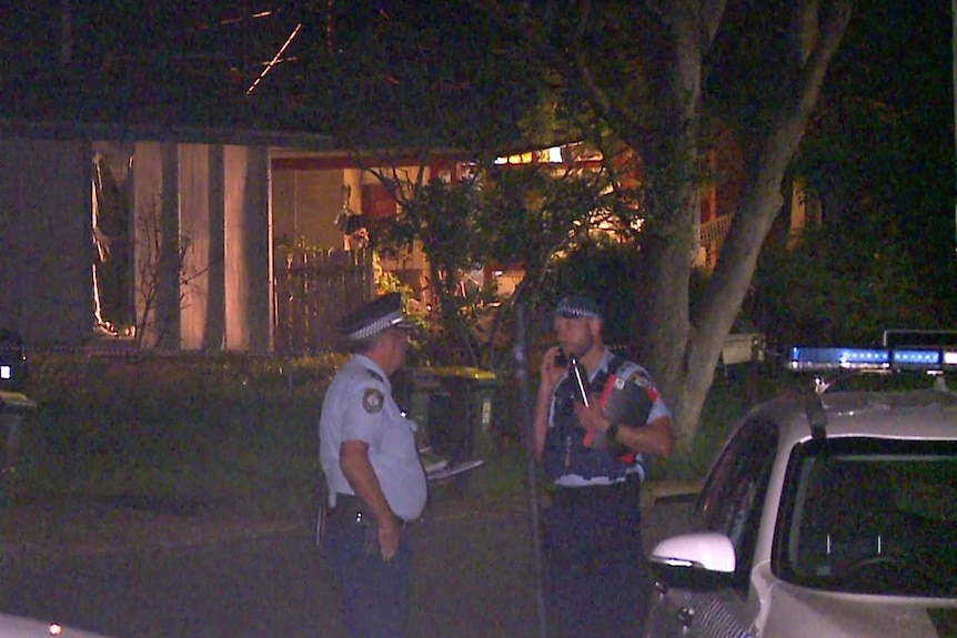 police officers standing in front of a suburban house