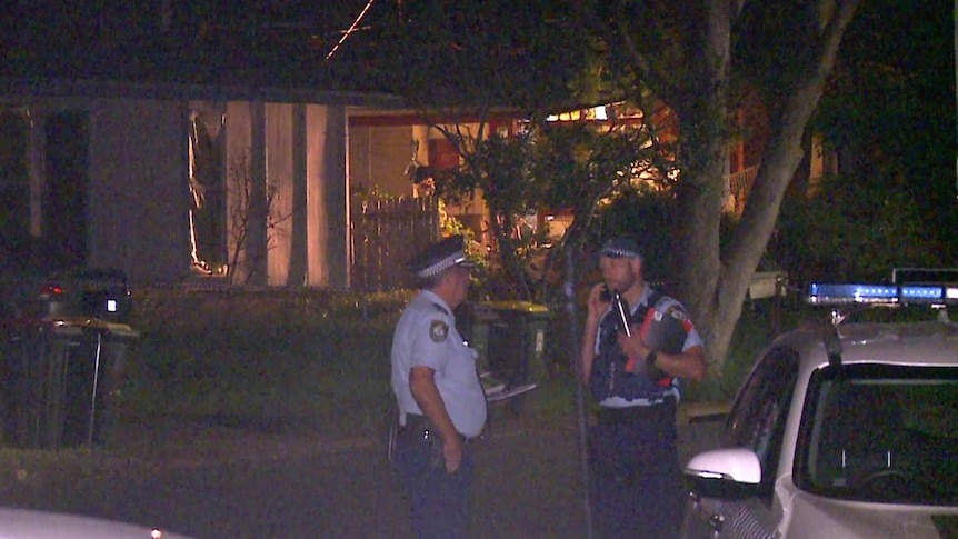 police officers standing in front of a suburban house