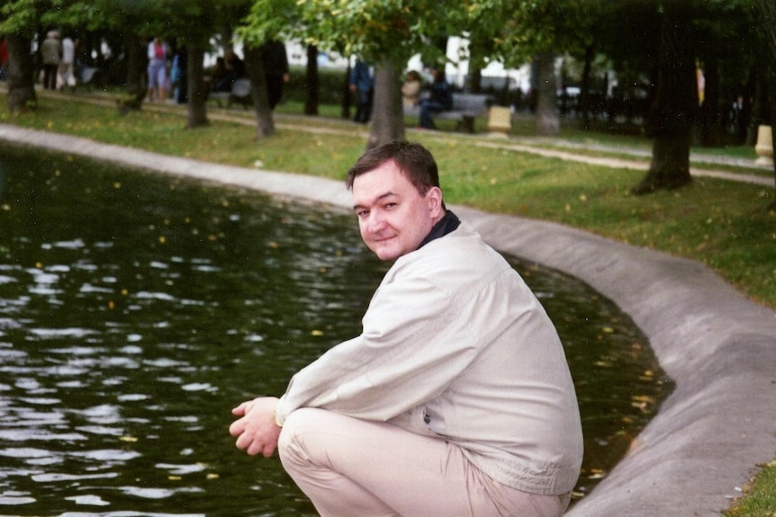 Sergei Magnitsky squatting by a pond in a park