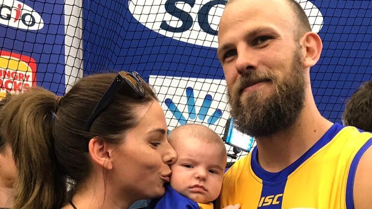 A bearded Eagles player with his wife and baby.