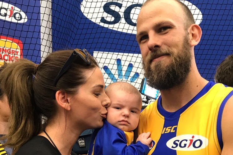 A bearded Eagles player with his wife and baby.