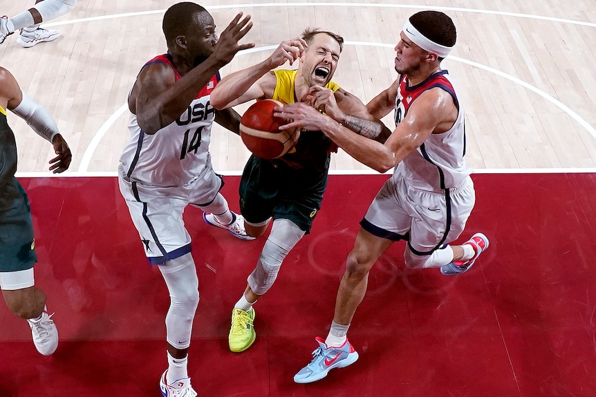 Nathan Sobey yells as he is flanked by Draymond Green and Devin Booker while trying to get a shot up