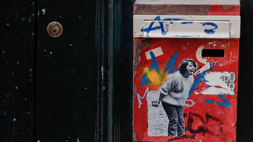 A letterbox with a picture on the outside of a person sticking their tongue out, in a story about how to write communal notes.