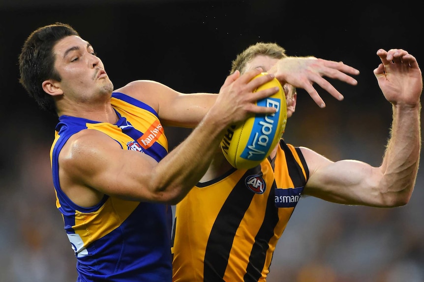 West Coast's Tom Barrass challenges Hawthorn's Ben McEvoy for possession during an AFL game, with a yellow football between them