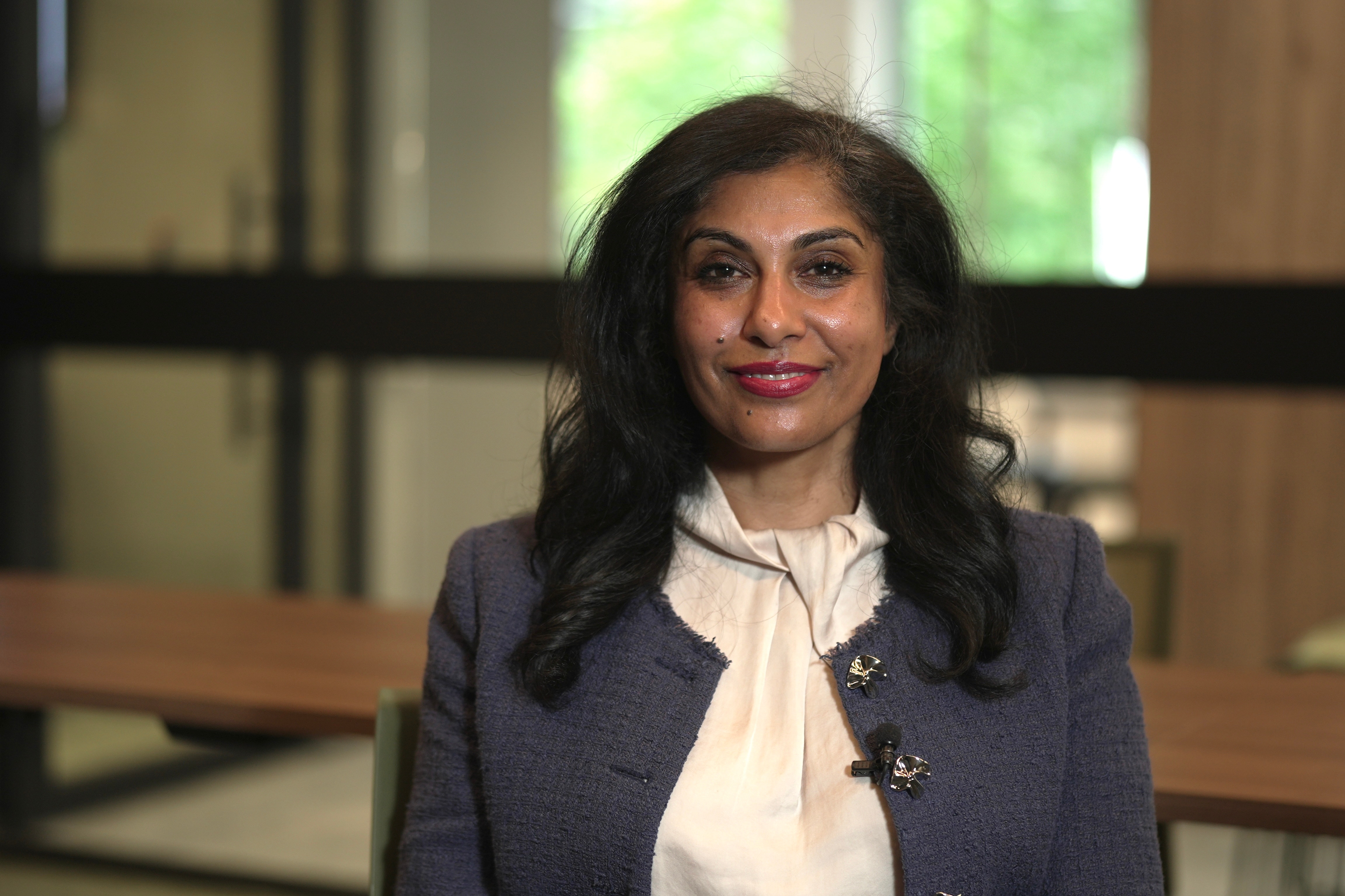 A woman in a suit and blouse smiles at camera.