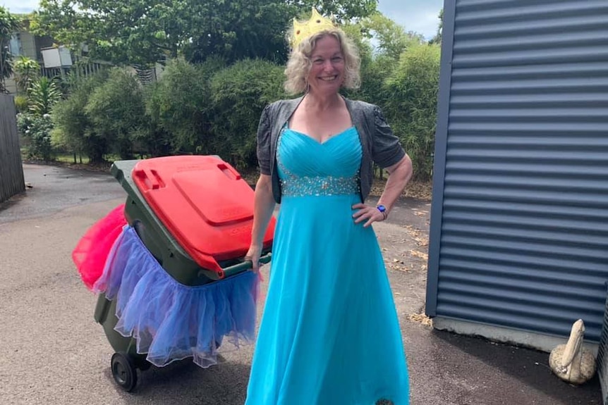 A woman in fancy dress dragging a wheelie bin with a tutu on it.