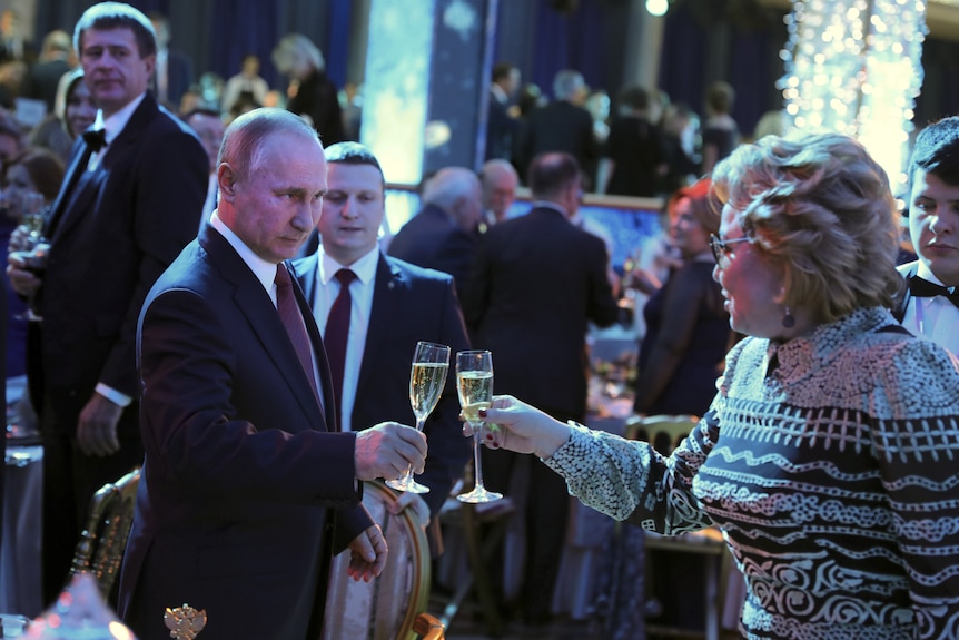 Vladimir Putin makes intense eye contact while clinking champagne flutes with a blonde woman