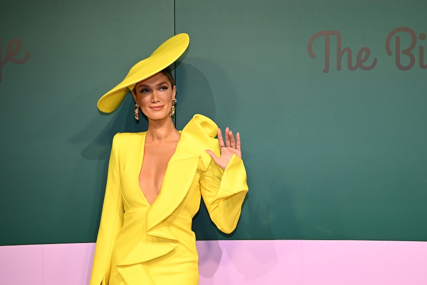 Delta Goodrem wearing yellow against a green backdrop at the Melbourne Cup.