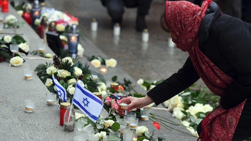 A woman places a candle at the memorial site in Berlin.