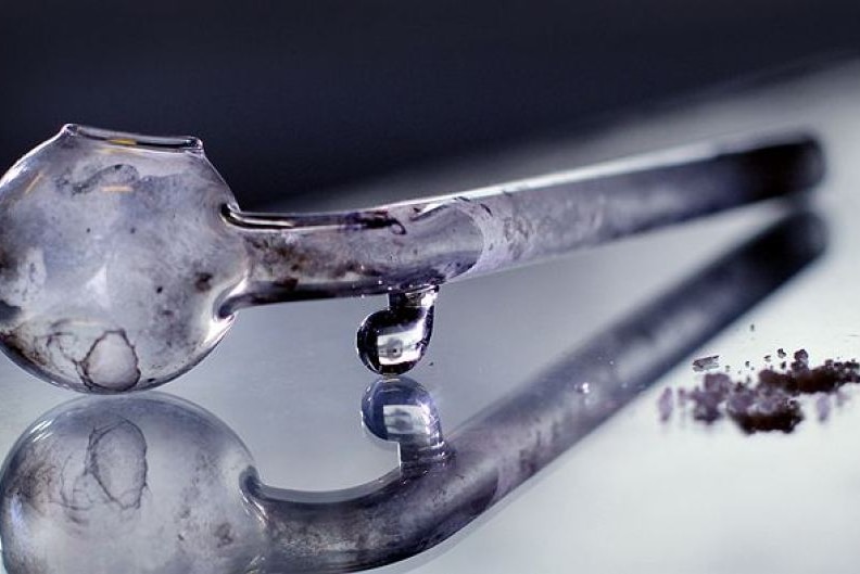 A glass methamphetamine pipe sits next to some ice