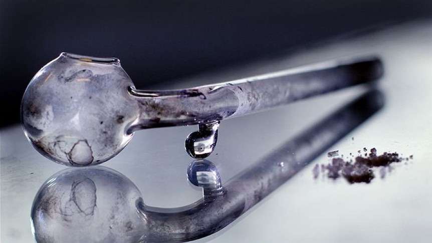 A glass methamphetamine pipe sits next to some ice