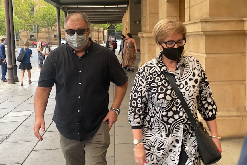 A man and a woman wearing black face masks walking outside a court building
