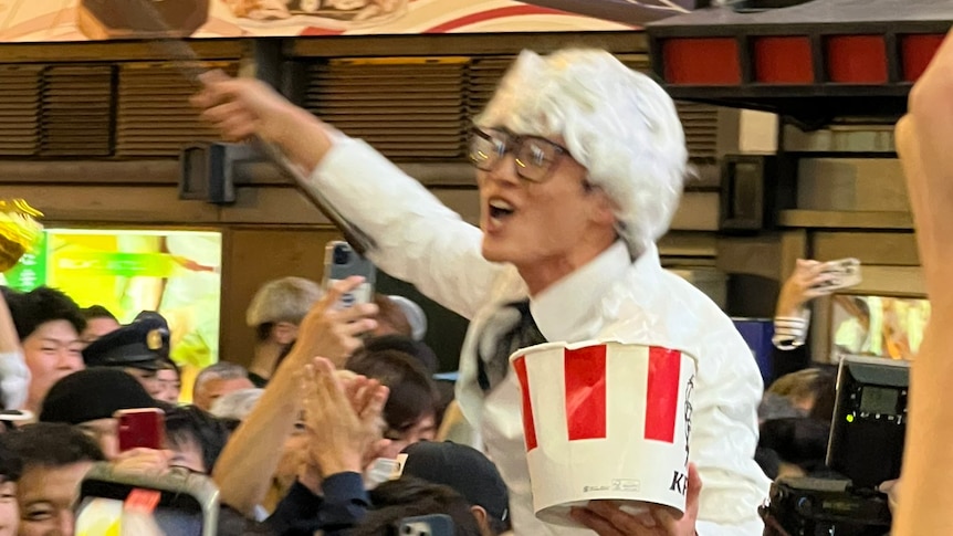 A Hanshin Tigers fan wearing Colonel Sanders costume and holding a KFC bucket