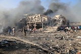 A general view shows the scene of an explosion in Mogadishu. There is smoke and a two-storey building has been reduced to rubble