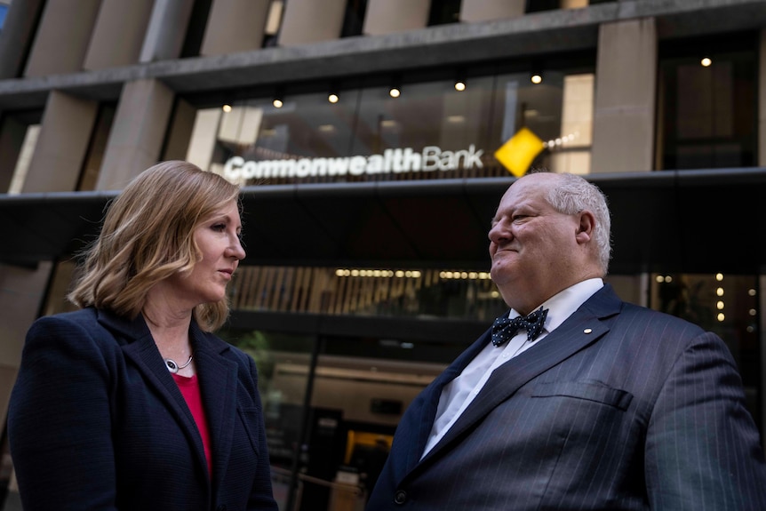 a man and a woman standing out the front of a commonwealth bank branch