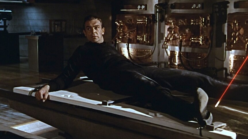 A still from the James Bond film Goldfinger where a man is strapped to a table with a laser pointing at his crotch