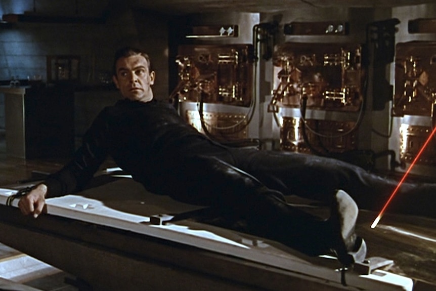 A still from the James Bond film Goldfinger where a man is strapped to a table with a laser pointing at his crotch
