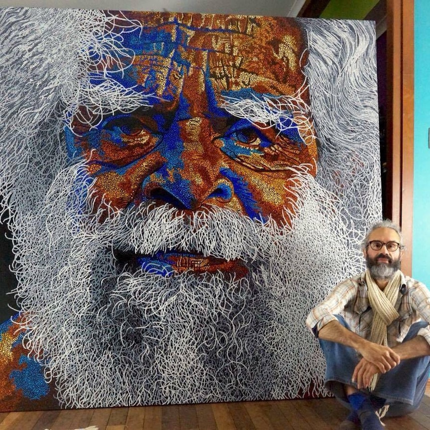 Artist sits in front of a two metre tall dot painting portrait