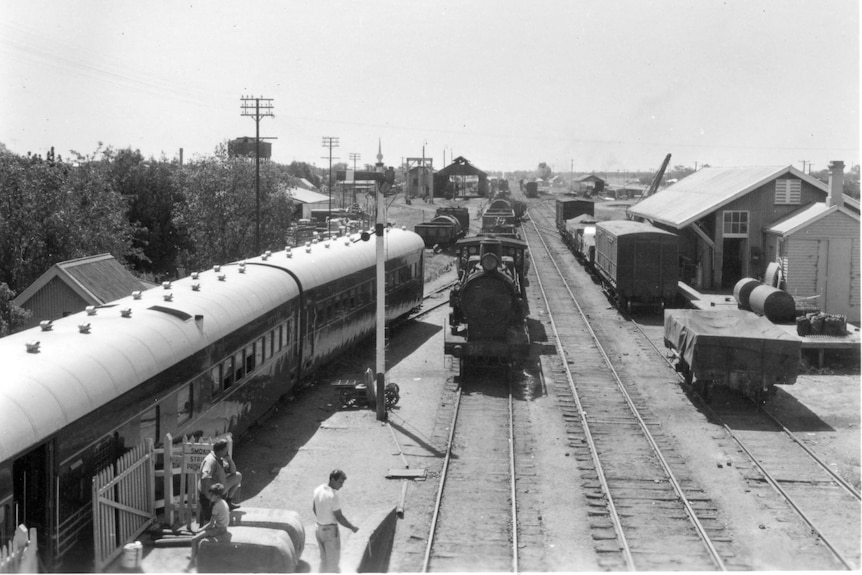 A black and white image overlooking the railway line in Nyngan, three trains on the tracks, people working 