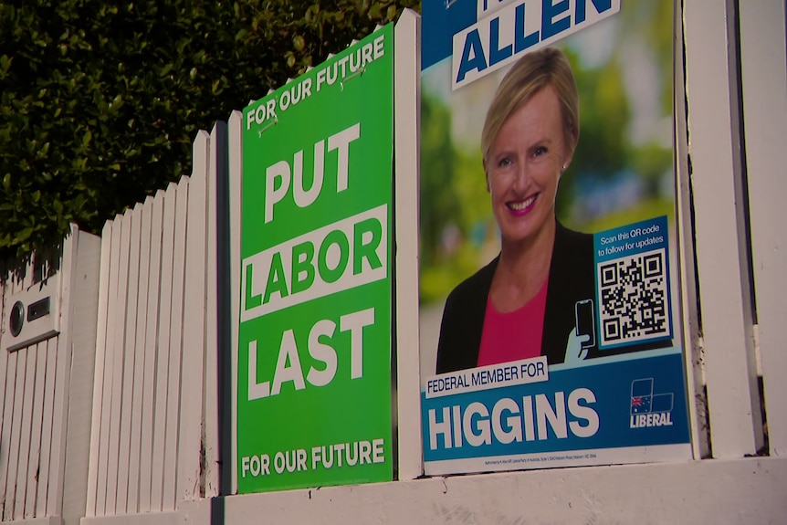Election signs on a white fence