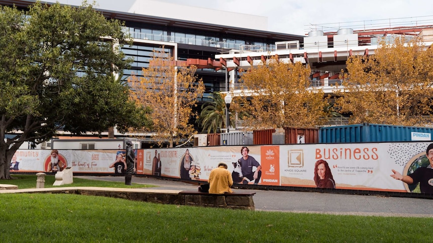 Building site with containers and hoardings surrounding half built buildings