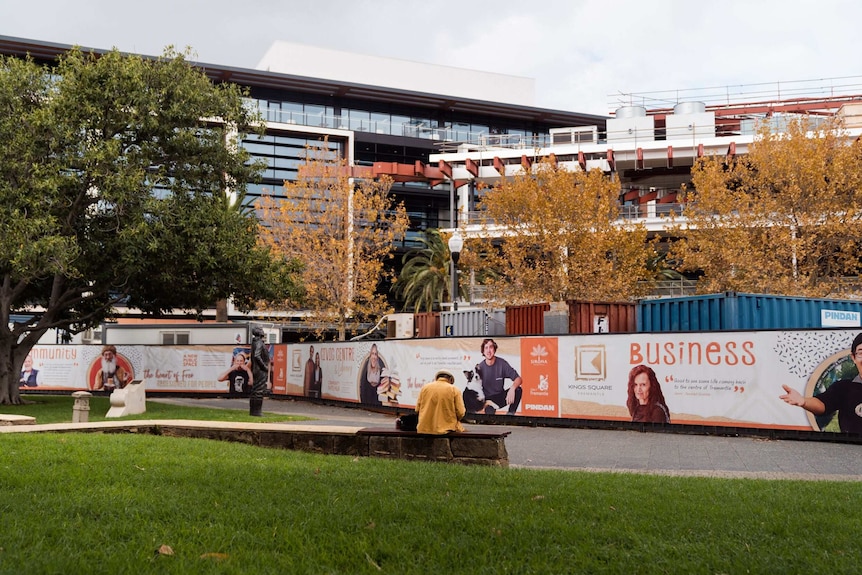 Building site with containers and hoardings surrounding half built buildings