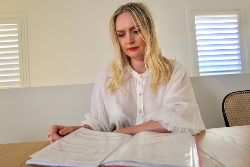 Tabitha West sits at a desk reading through a folder of court documents.