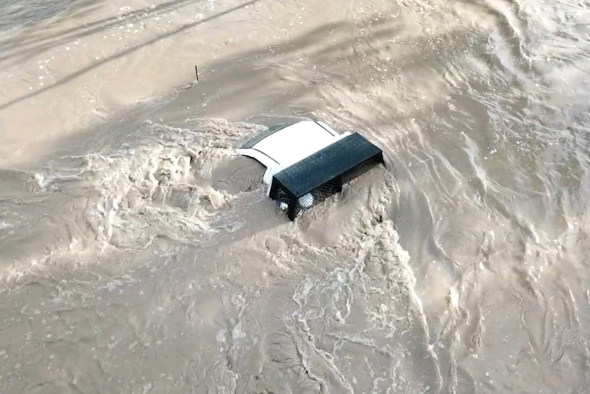Roof of a ute almost competely submerged in floodwaters