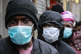People wearing face masks wait in a line for food in Harlem.