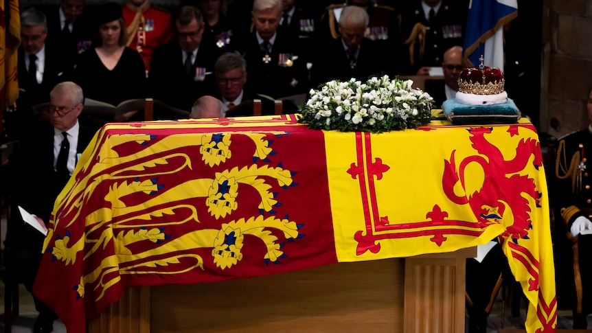 A crown sits on a coffin draped in the royal flag