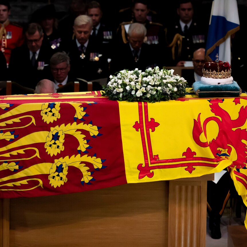 A crown sits on a coffin draped in the royal flag