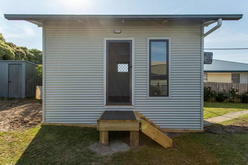 A small granny flat with a step and flat roof situated in a backyard