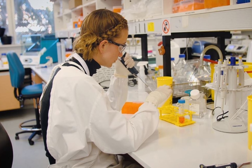 A woman with safety glasses and lab coat.