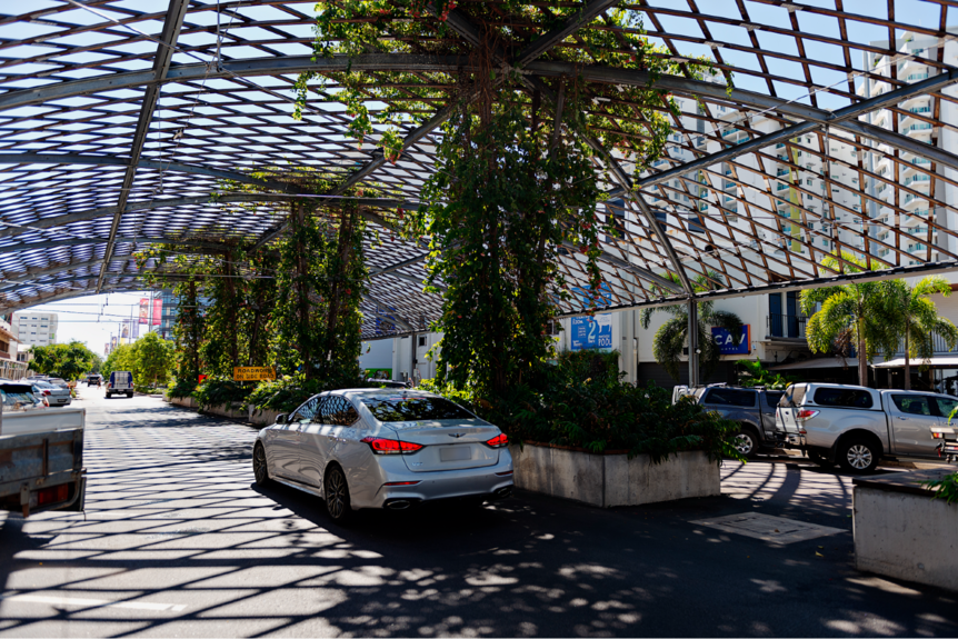 A silver car drives through a wooden, lattice shade structure in the Darwin CBD.