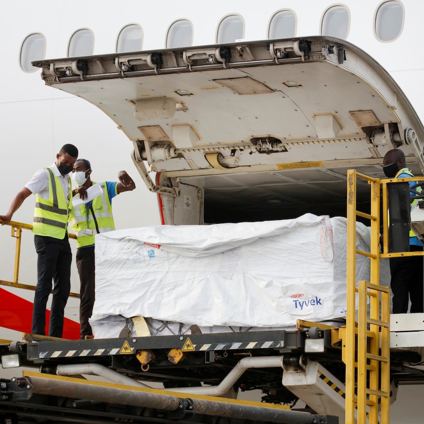 Workers use a hydraulic lift to unload boxes from a plane.