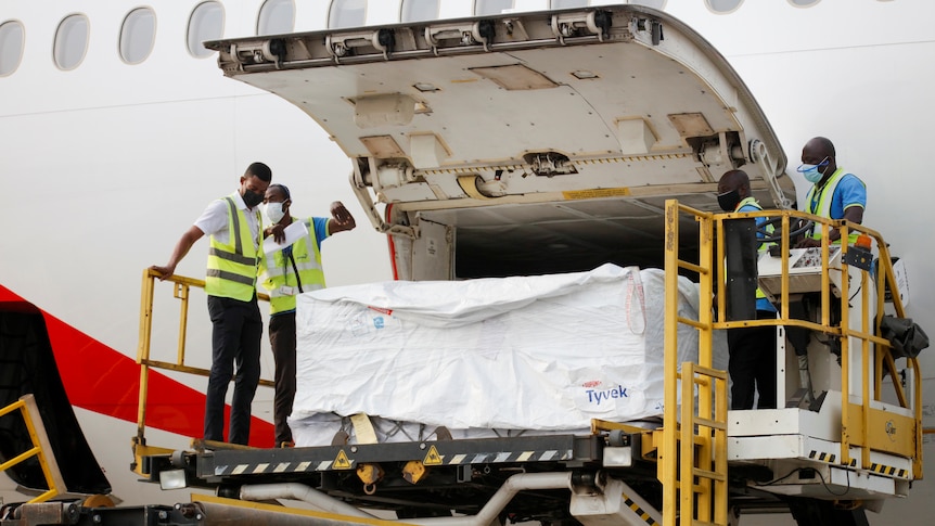 Workers use a hydraulic lift to unload boxes from a plane.