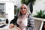 A lady sits at a table outside