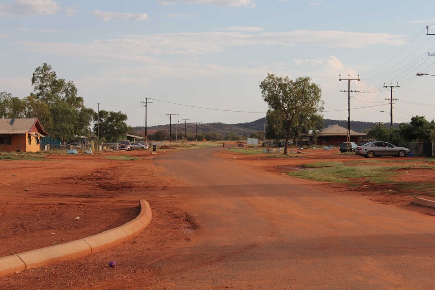 Rubbish is strewn across dusty red roads and cars are parked in driveways in Yuendumu.