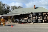 A truck on its side with its wheels in the air and road blocked off.