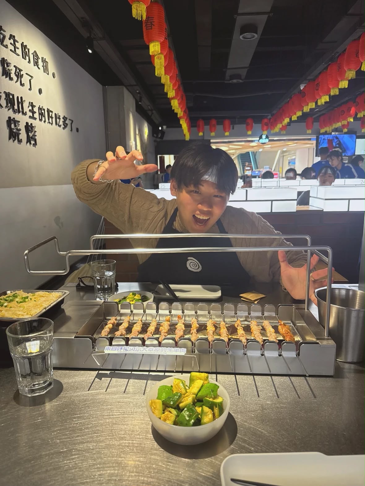 A man wearing headband looking at a food on a table while raising his hand.