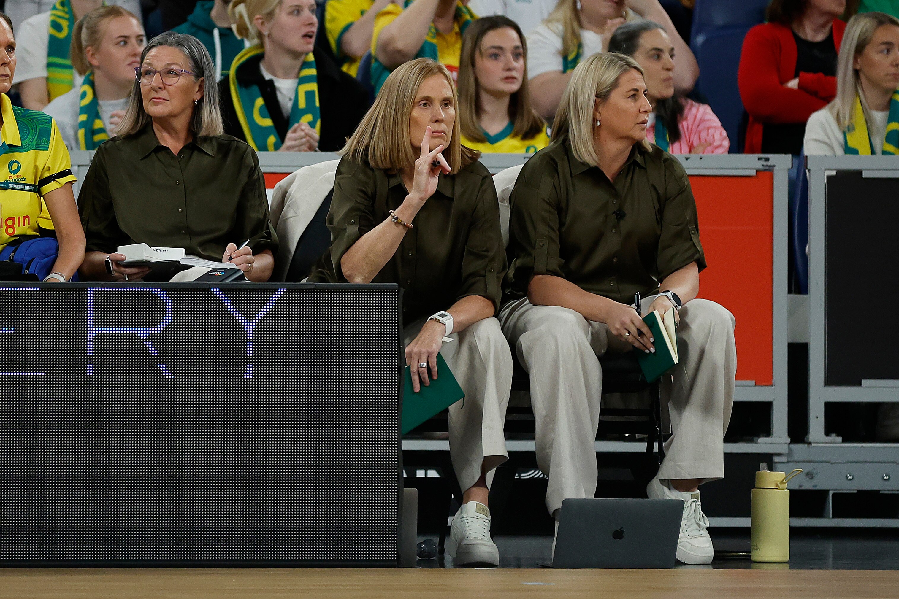 Two coaches sit on the sideline, as one gestures to players