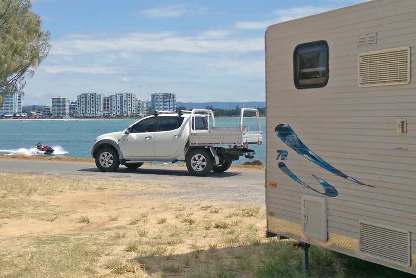 A jet ski goes past campers on The Spit, Gold Coast