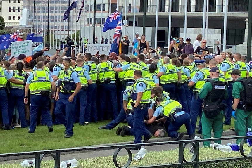 An anti-vaccine mandate protester is detained as dozens of police clash with protesters