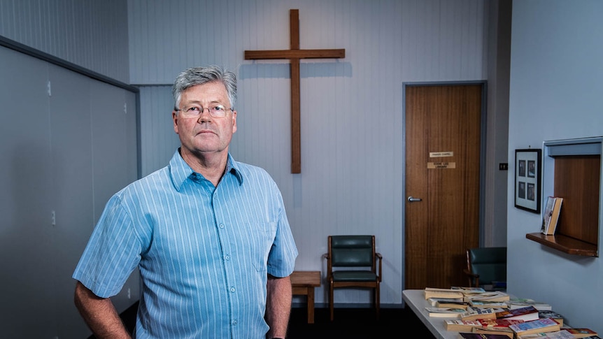 Grant Stewart poses for a portrait in front of a wooden cross at His East Doncaster Baptist Church in Melbourne.