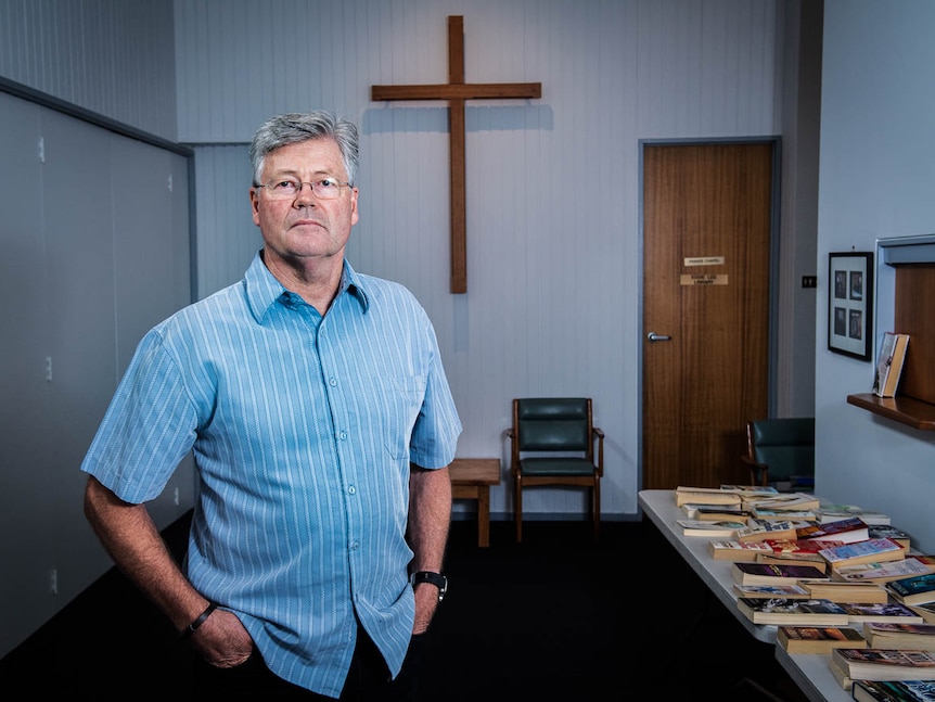 Grant Stewart poses for a portrait in front of a wooden cross at His East Doncaster Baptist Church in Melbourne.