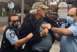 A man being arrested and held by two police officers.