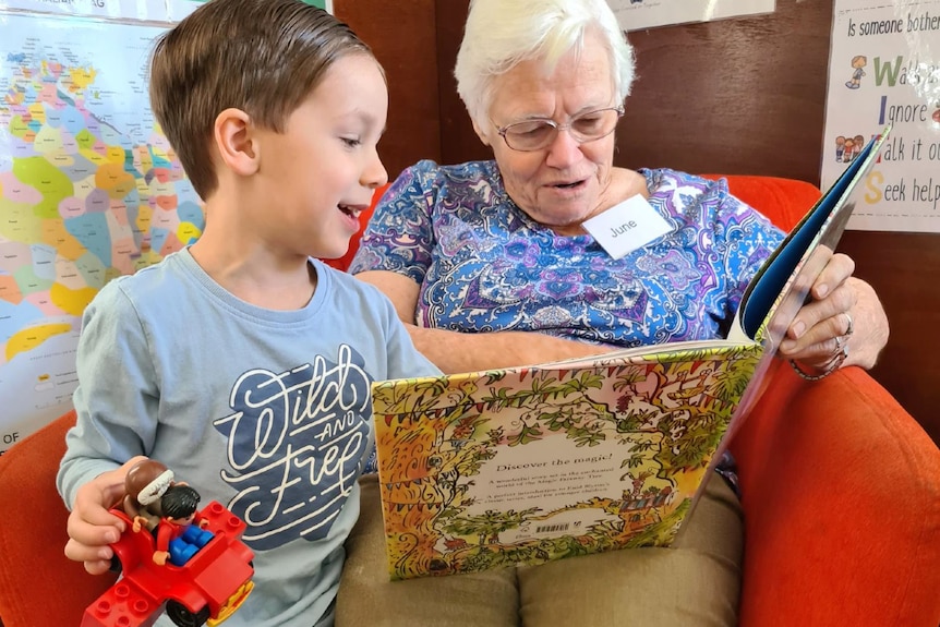 Female senior and young child reading in a chair