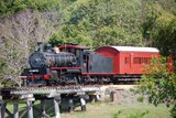 historic steam train crossing a bridge in rural area