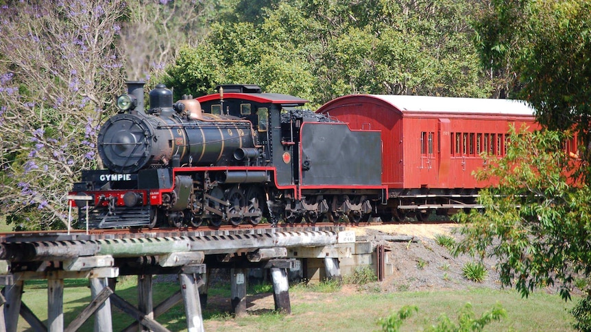 historic steam train crossing a bridge in rural area