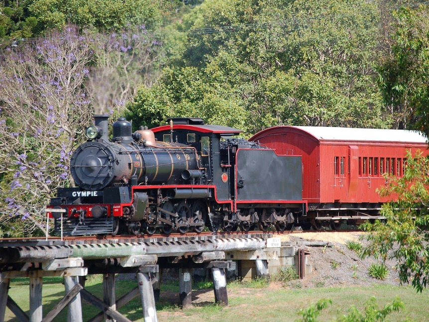 historic steam train crossing a bridge in rural area